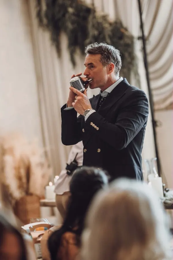 Howard Wing singing among seated wedding guests